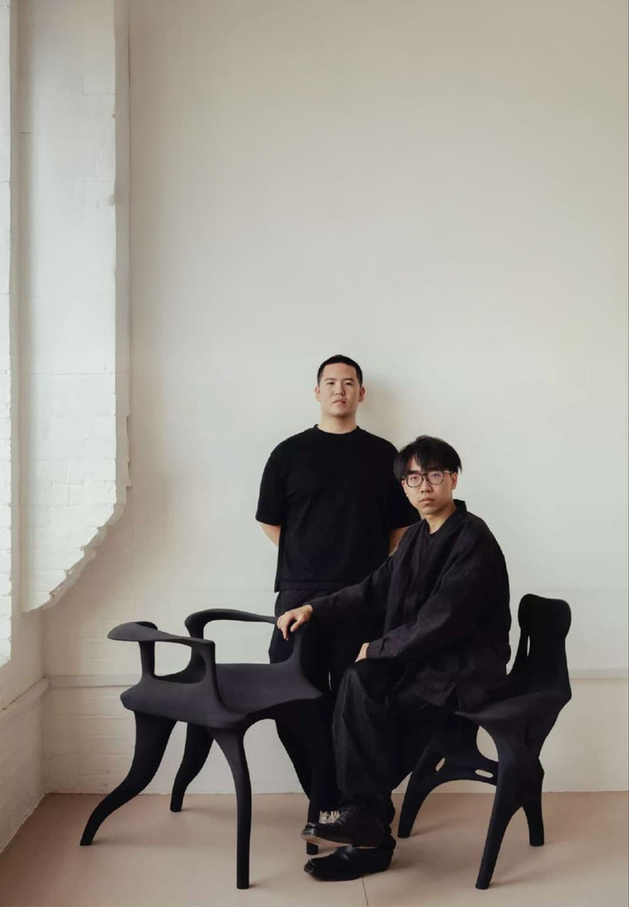 Peiyan Zou and Ray Zhang in their studio, with two chairs they designed.
